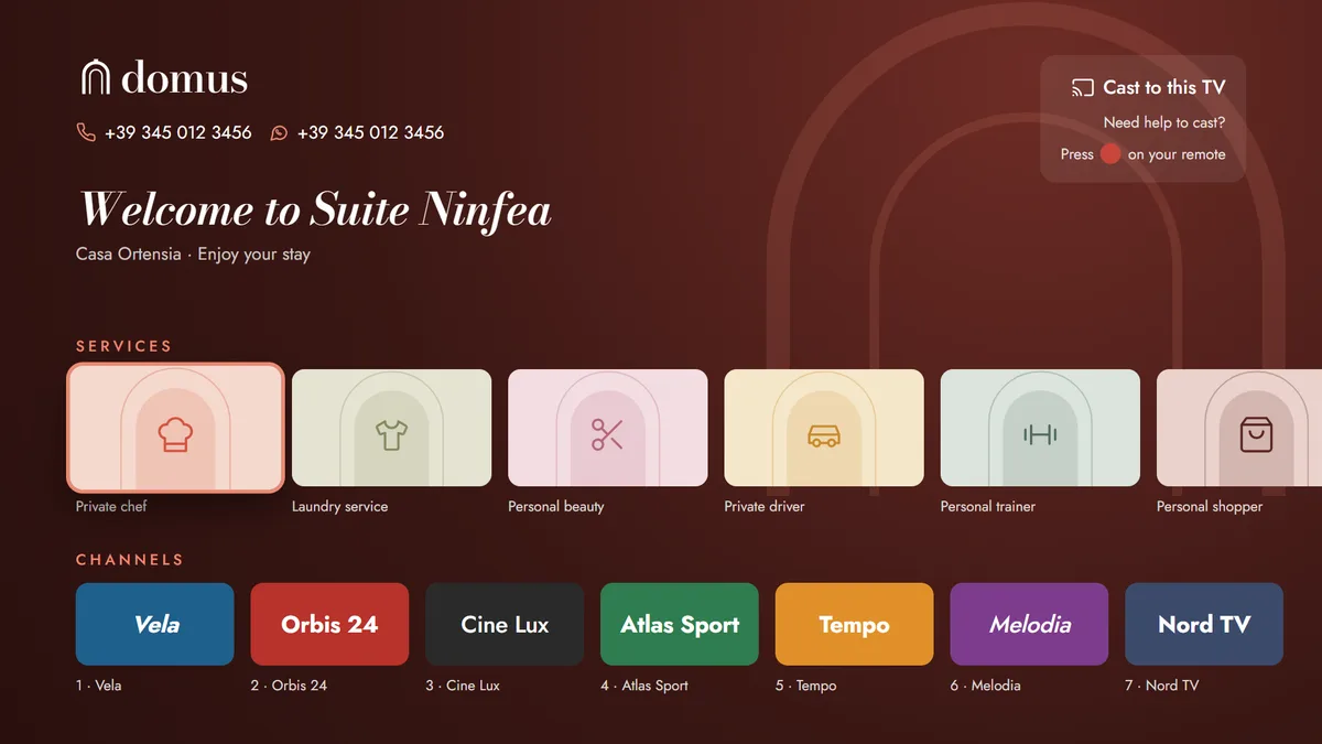 Dark red TV homepage welcoming the guest to Suite Ninfea with the concierge phone and WhatsApp numbers, a cast help box, a row of service tiles with the private chef in focus and a row of channel logos